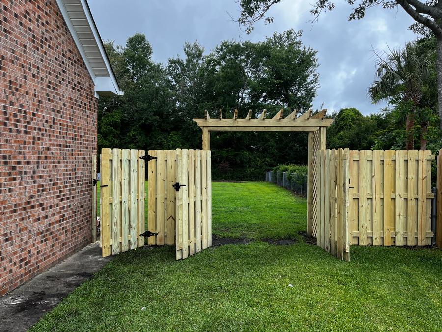 Double gates standing open under a wooden pergola